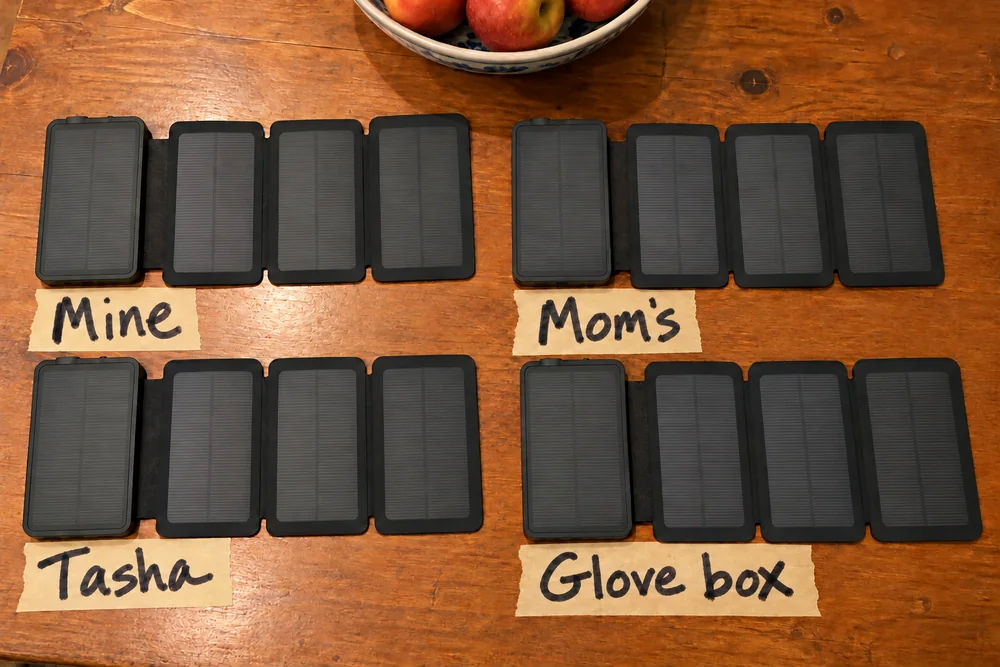 Four TerraCells laid open on a kitchen table, each over a strip of masking tape labeled Mine, Mom's, Tasha and Glove box
