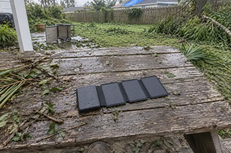 TerraCell opened on a wet picnic table the morning after a hurricane, the yard full of broken branches, a blue tarp on the roof next door