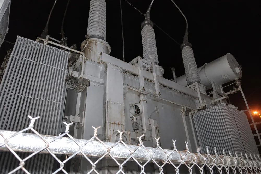 A flash photo at night through the substation fence: the giant transformer towering two storeys overhead