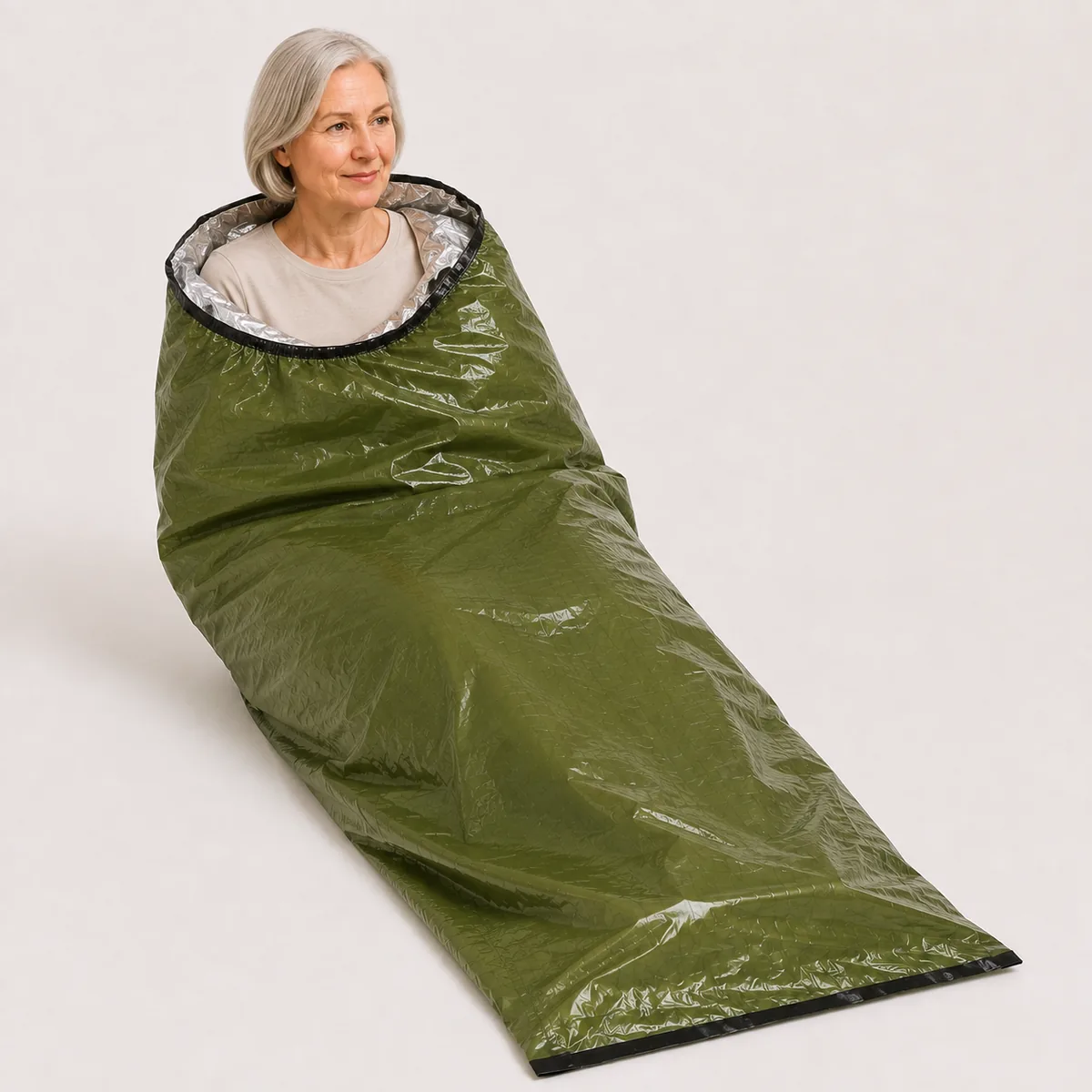 A woman in her sixties sits inside an opened TerraShell pulled up to her shoulders, the silver lining showing at the opening