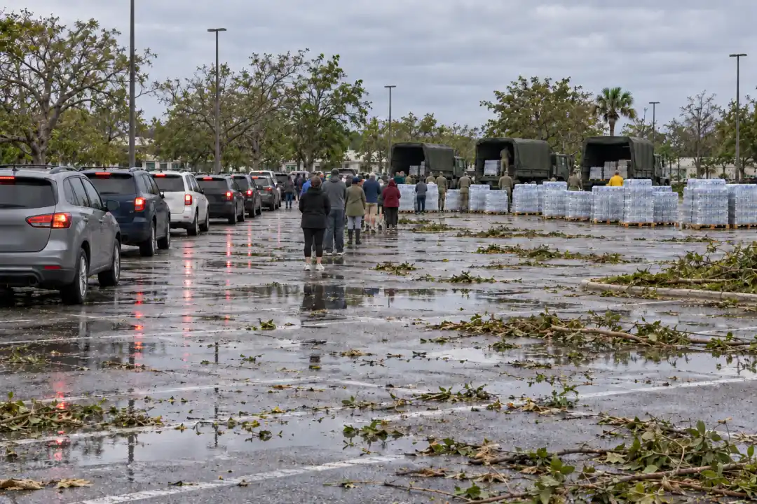 After a hurricane, a long line waits for cases of water at a parking lot.