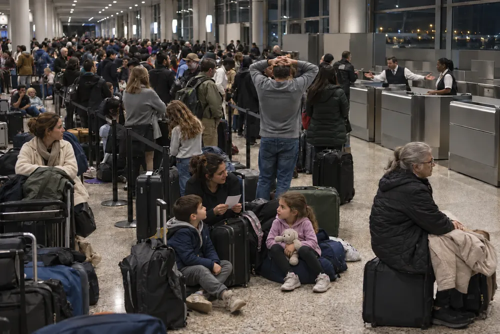 A crowded airport hall at night, stranded travelers waiting in a long line and sitting on the floor with their bags