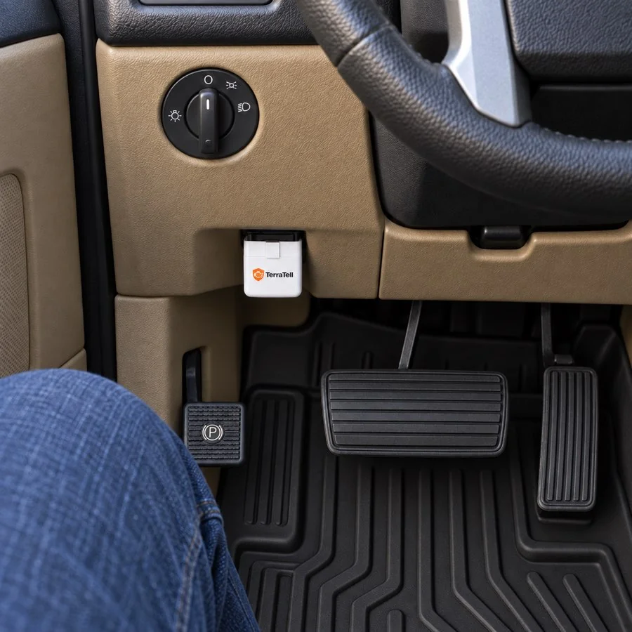 A driver's knee by the pedals and TerraTell pushed into the socket under the dash.